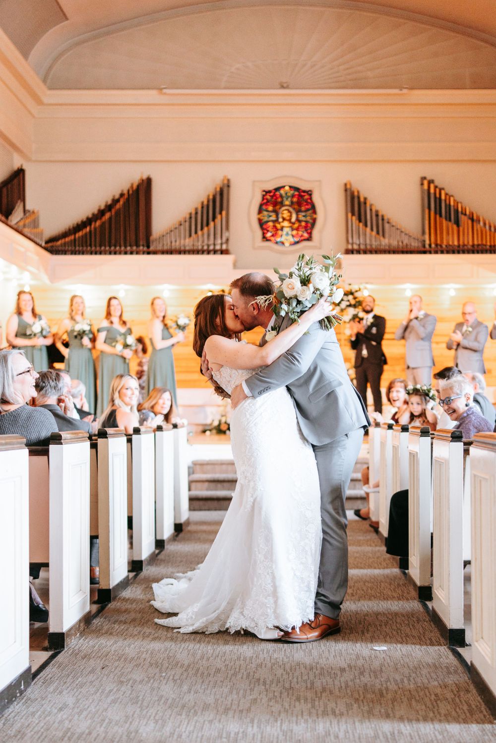 A wedding ceremony in a traditional church with bridesmaids in blue dresses and a pipe organ in the background.