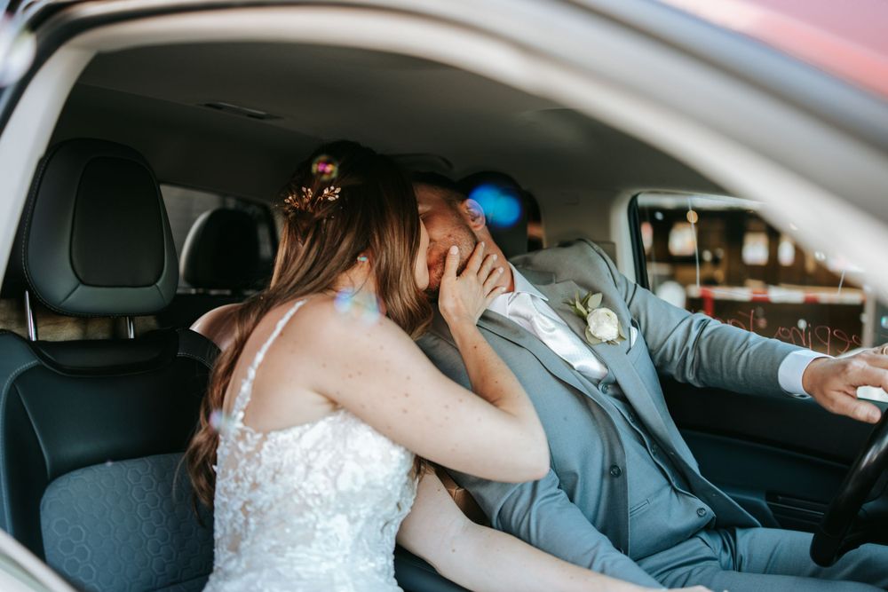 A candid moment captured of newlyweds laughing together in their car.