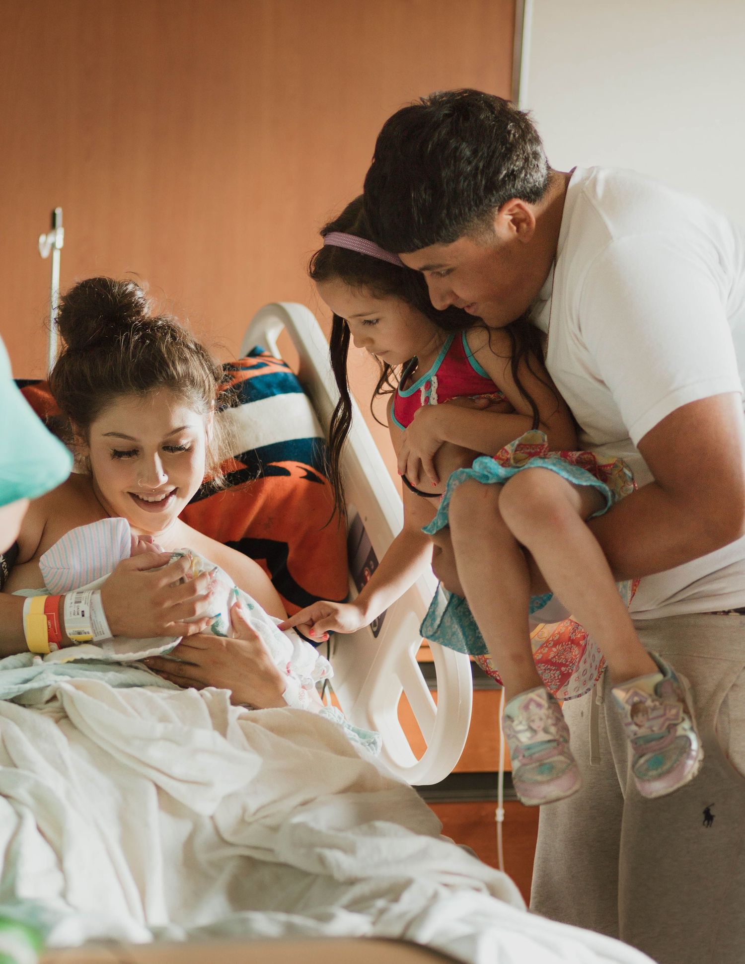 A joyful family gathering around a hospital bed to welcome their newest member.