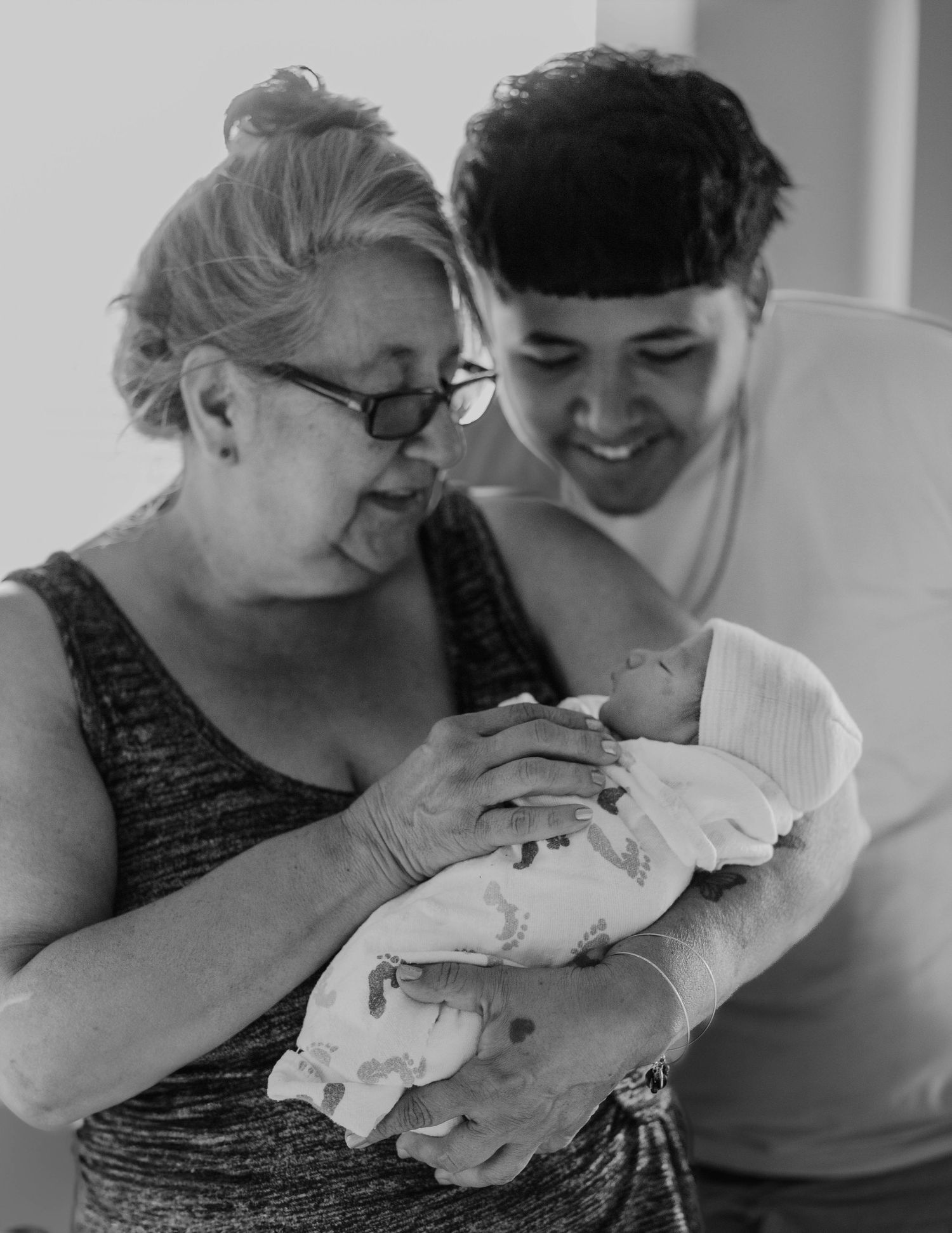 A black and white photograph capturing a tender moment with a newborn baby in a hospital setting.