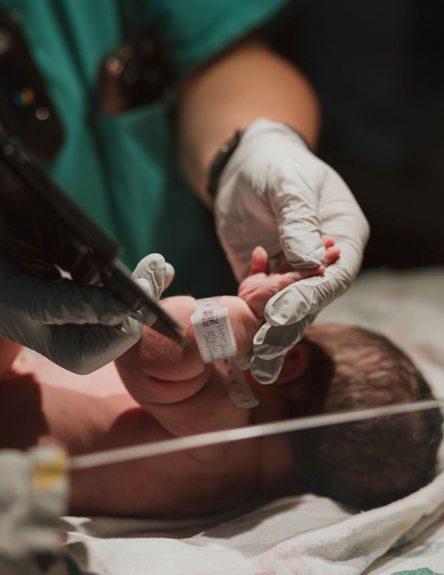 Medical professional in gloves performing newborn care procedures in a hospital setting.
