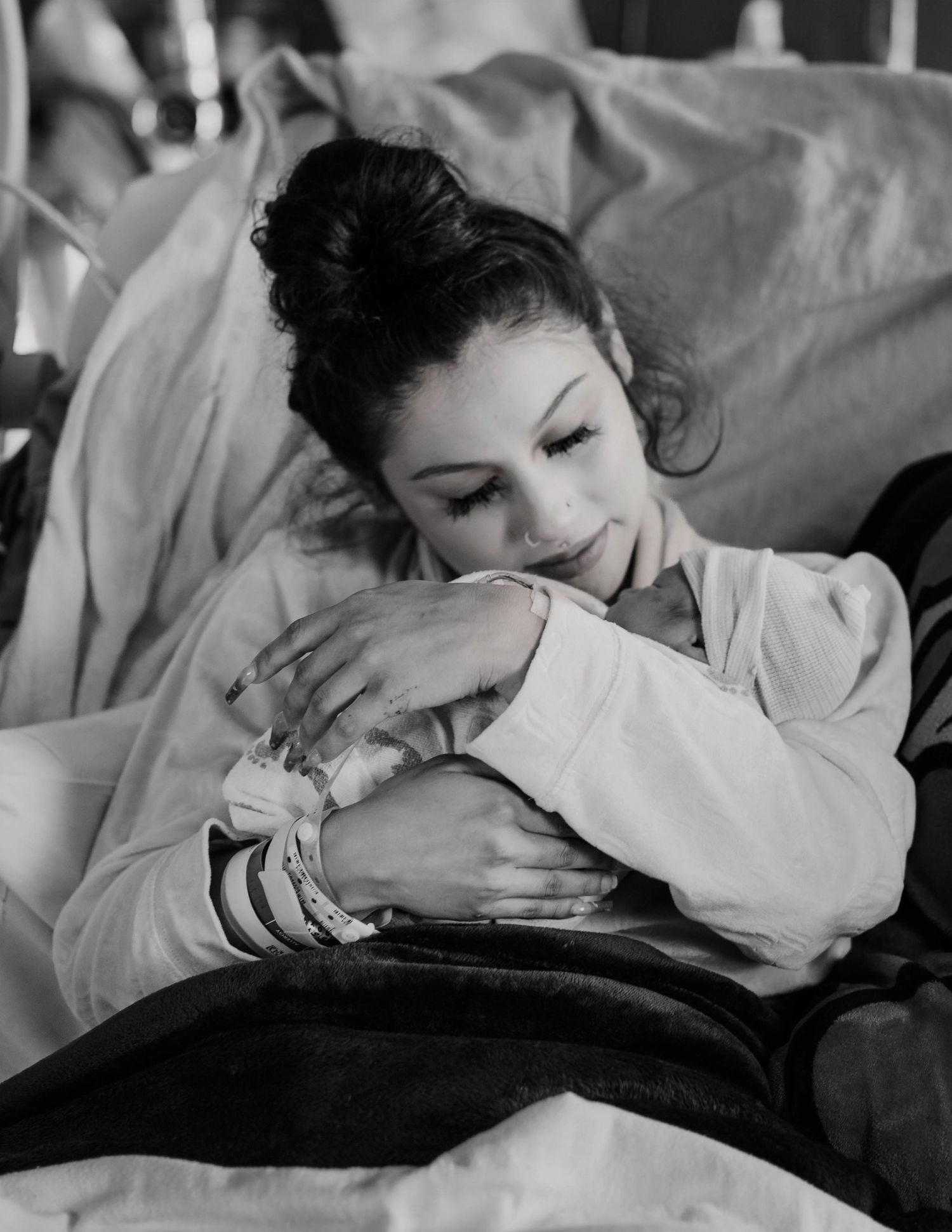 A black and white photograph shows someone resting peacefully in bed while hugging a pillow.