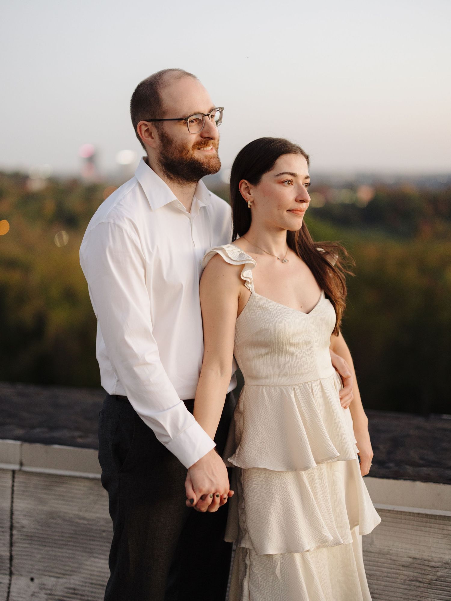 A romantic sunset portrait of a couple in formal attire standing together on an outdoor deck.