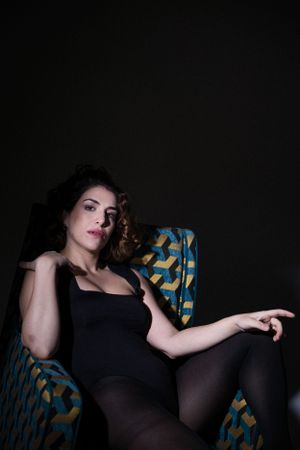 Low light portrait on patterned furniture with dramatic shadows.