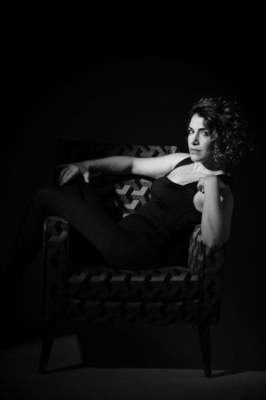 Artistic black and white photo of figure gracefully posed on vintage chaise lounge.