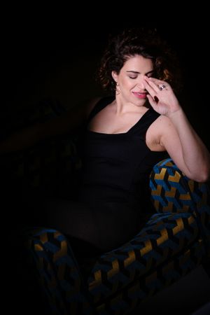 Moody boudoir portrait showing intimate moment on patterned furniture with dramatic shadows.