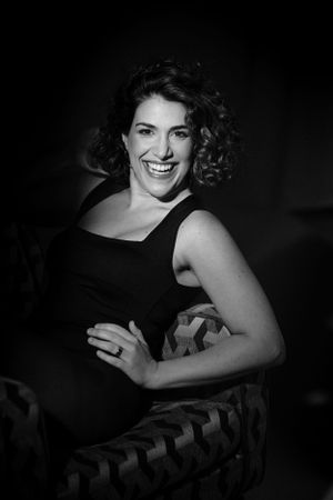 Black and white portrait showing joyful expression and curly hair against dramatic lighting.