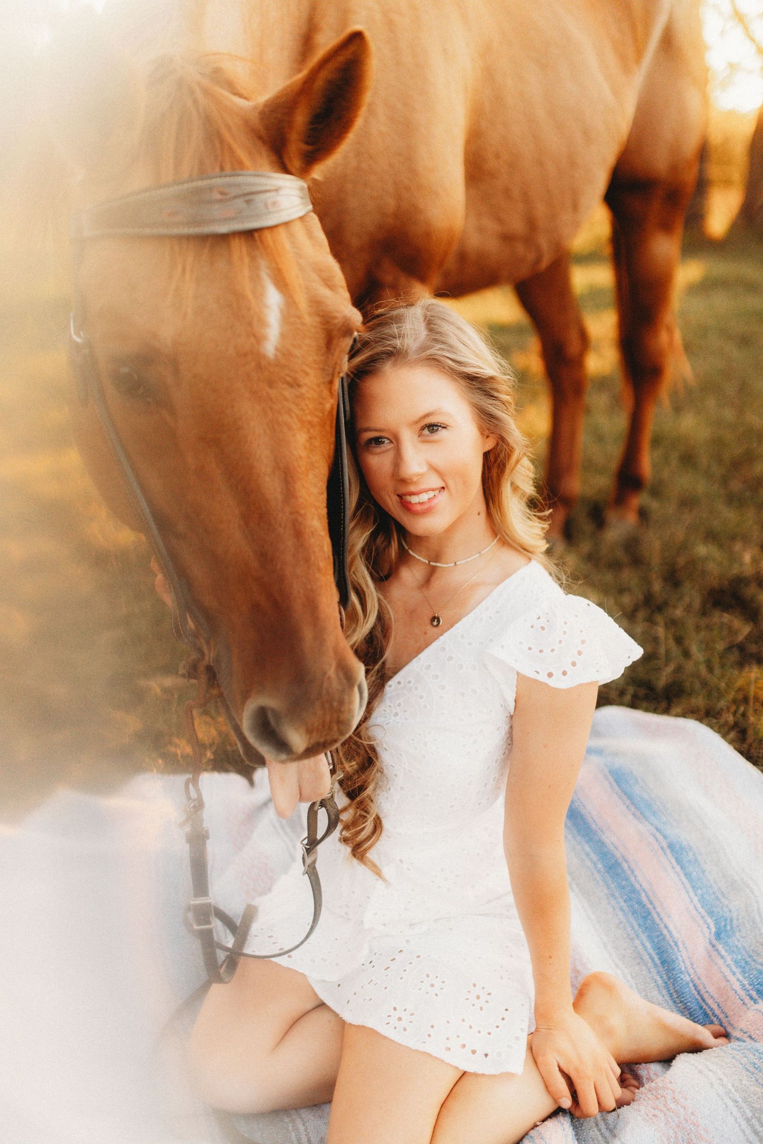 Senior girl sitting on the ground with her horse next to her