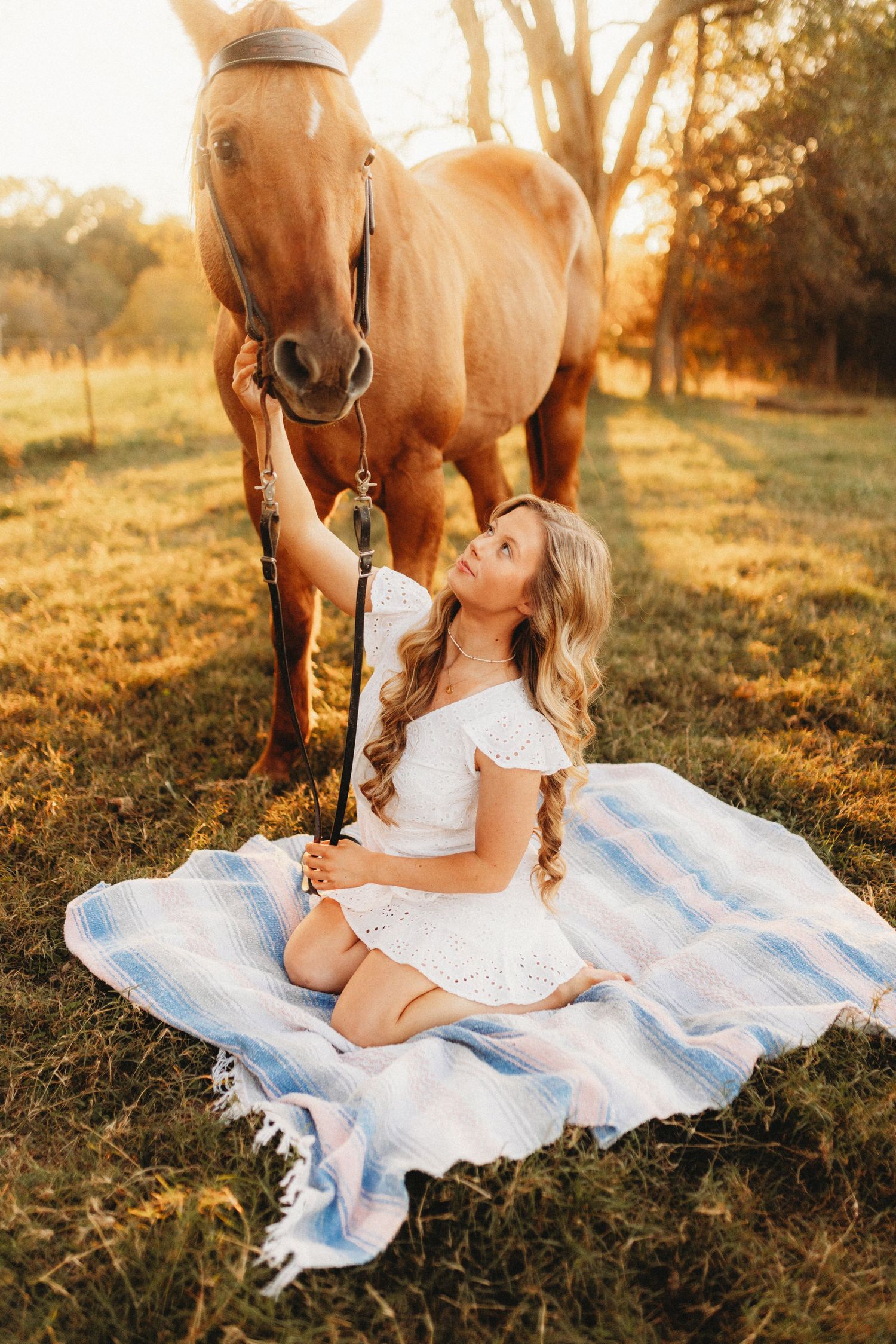 Senior girl sitting on the ground with her horse next to her