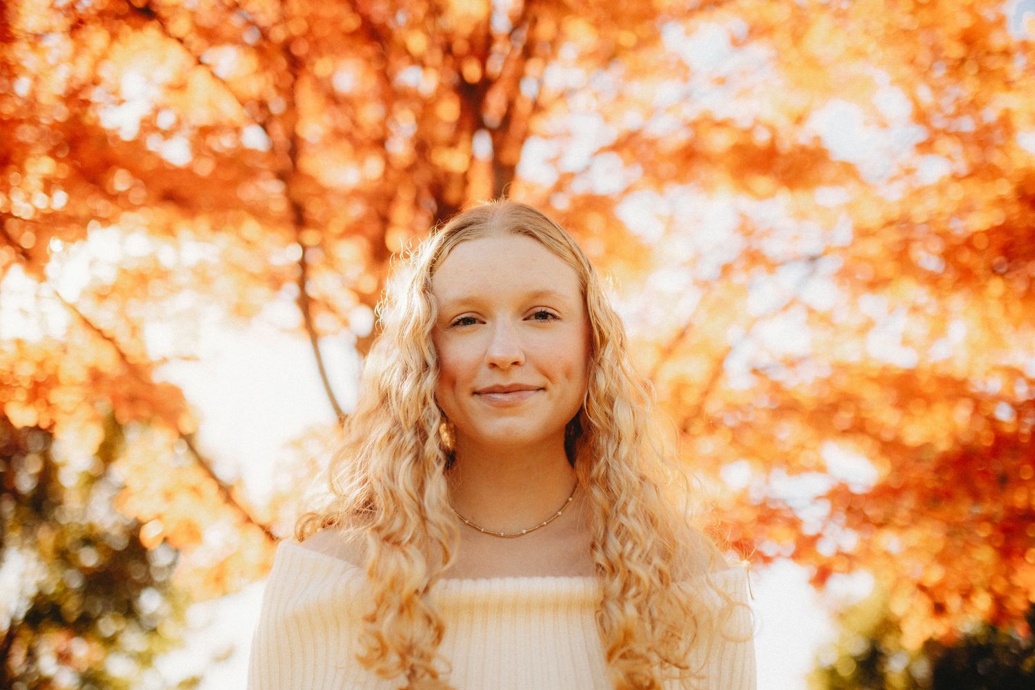 Senior girl with orange fall leaves above her head