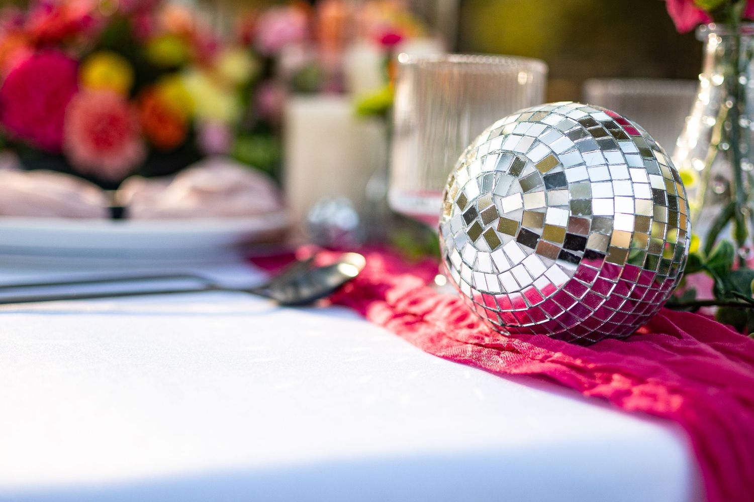 Decorative mirror disco ball on pink table runner at a festive wedding reception.