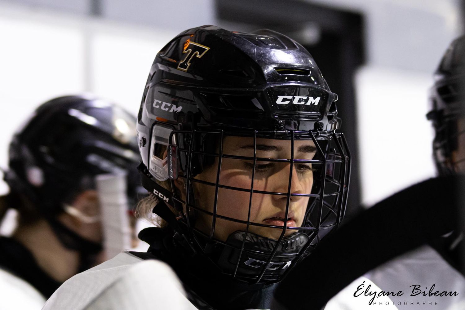 Close up of hockey player wearing black CCM helmet and protective gear during game.