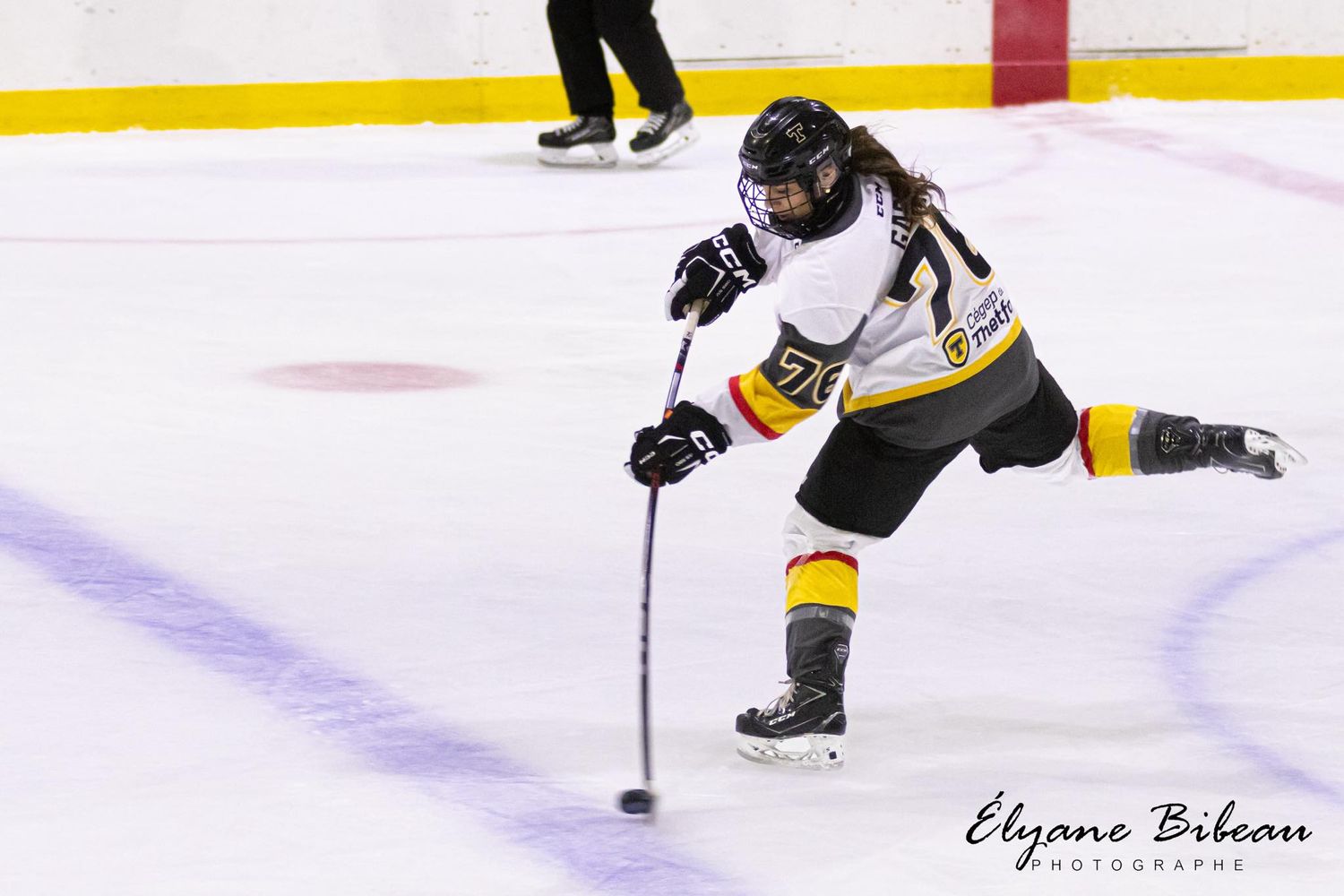 Hockey player in motion taking a shot on ice during game.