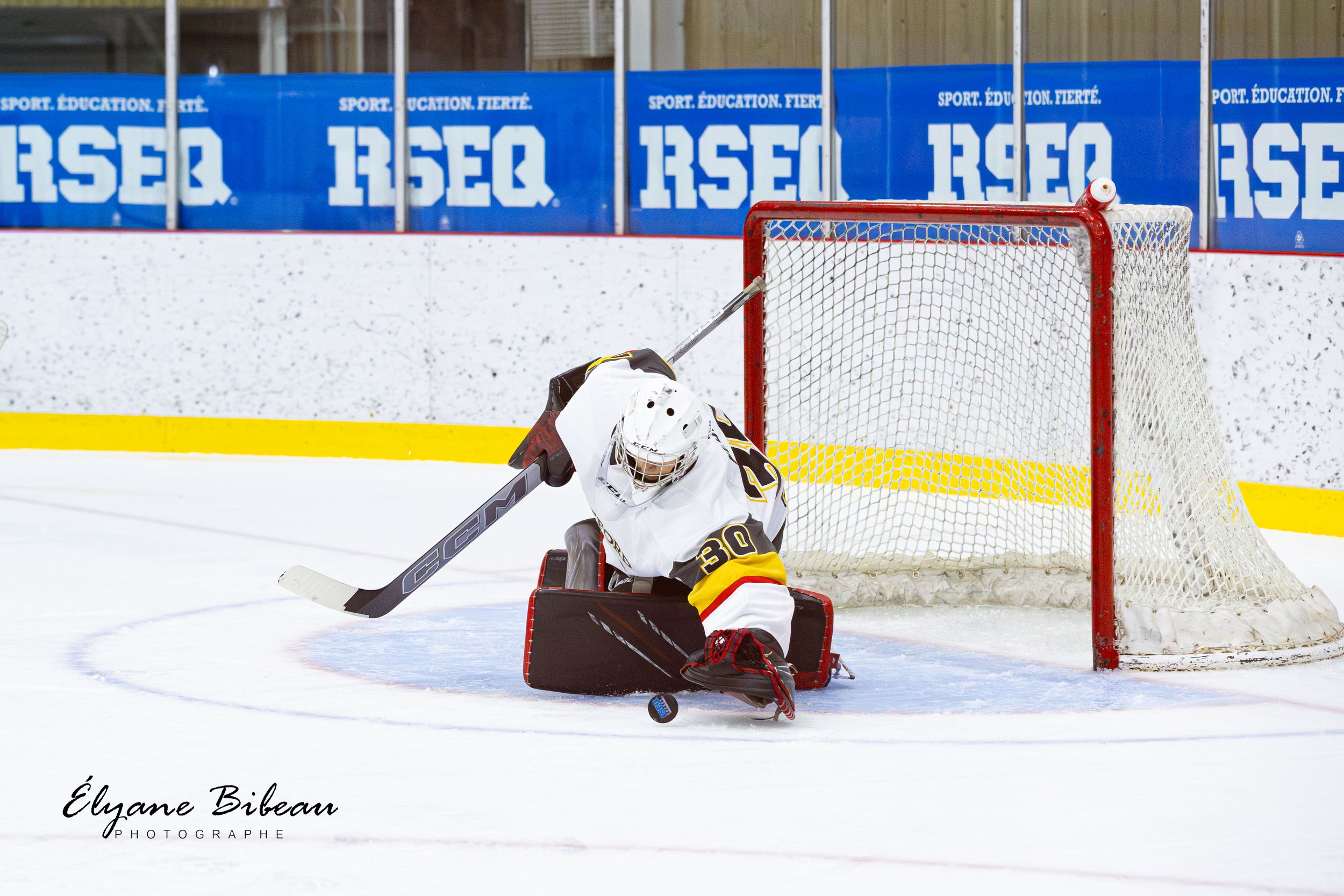 A hockey goalie makes a diving save to protect the net during a game.