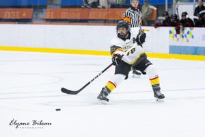 Hockey player in yellow and white uniform controls the puck during gameplay.