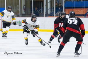 Hockey player in white jersey maneuvers with the puck while being defended.