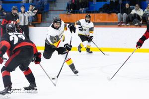 Hockey players from opposing teams battle for puck control on the ice.