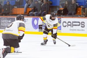 Hockey player maneuvers with puck during intense game action.