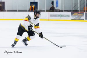 Hockey player in black and yellow uniform handles puck on ice during game.
