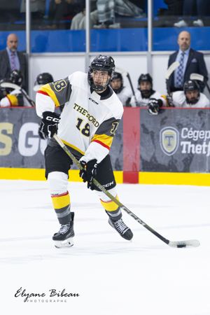 Hockey player wearing number 16 controls puck during game.