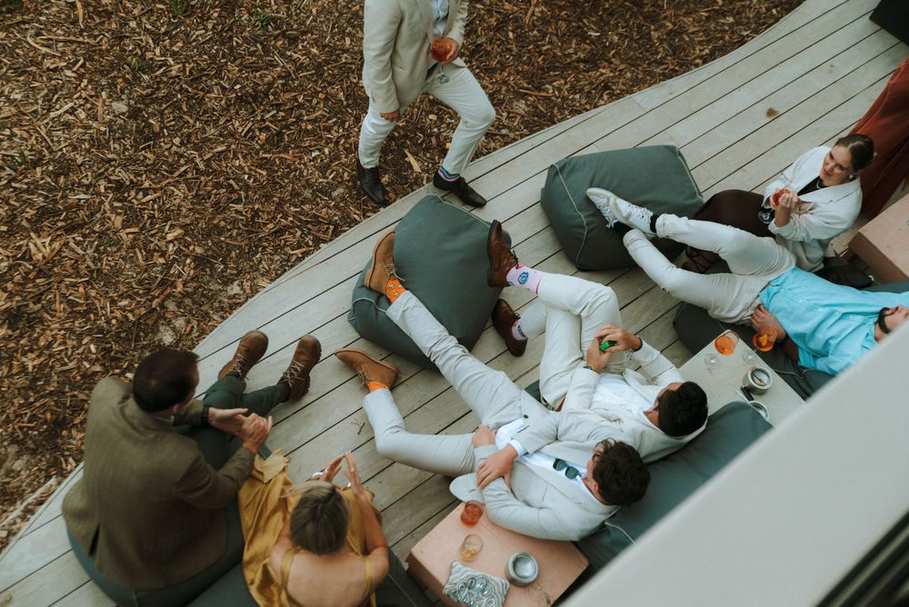 People sitting at a wooden picnic table in a park having a casual outdoor gathering.