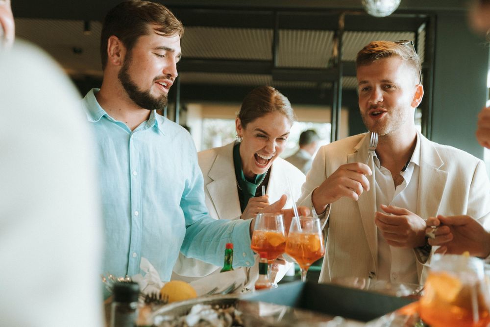 A group of friends laughing and enjoying cocktails together at a restaurant bar.