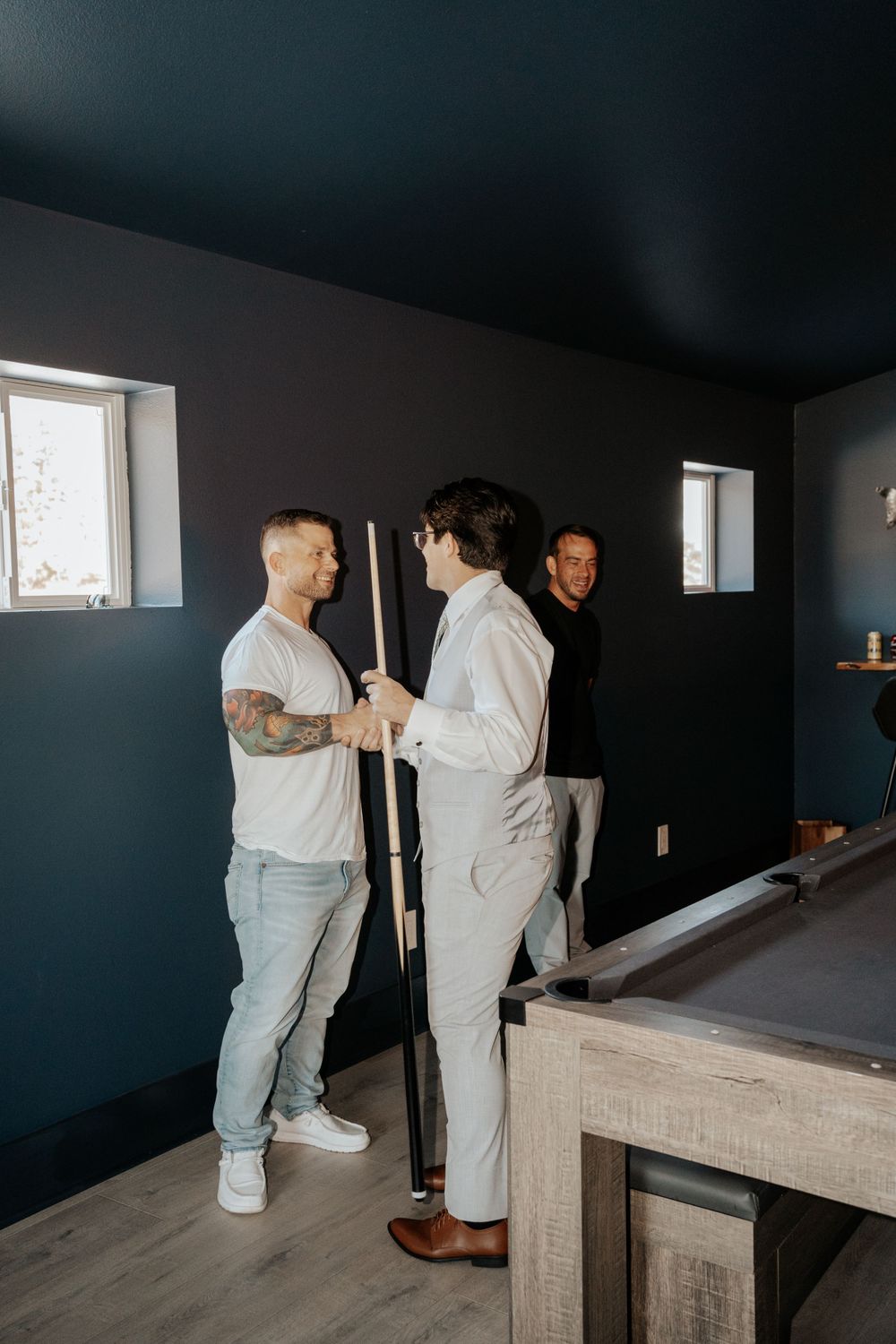 Casual gathering in game room with pool table and dark walls.