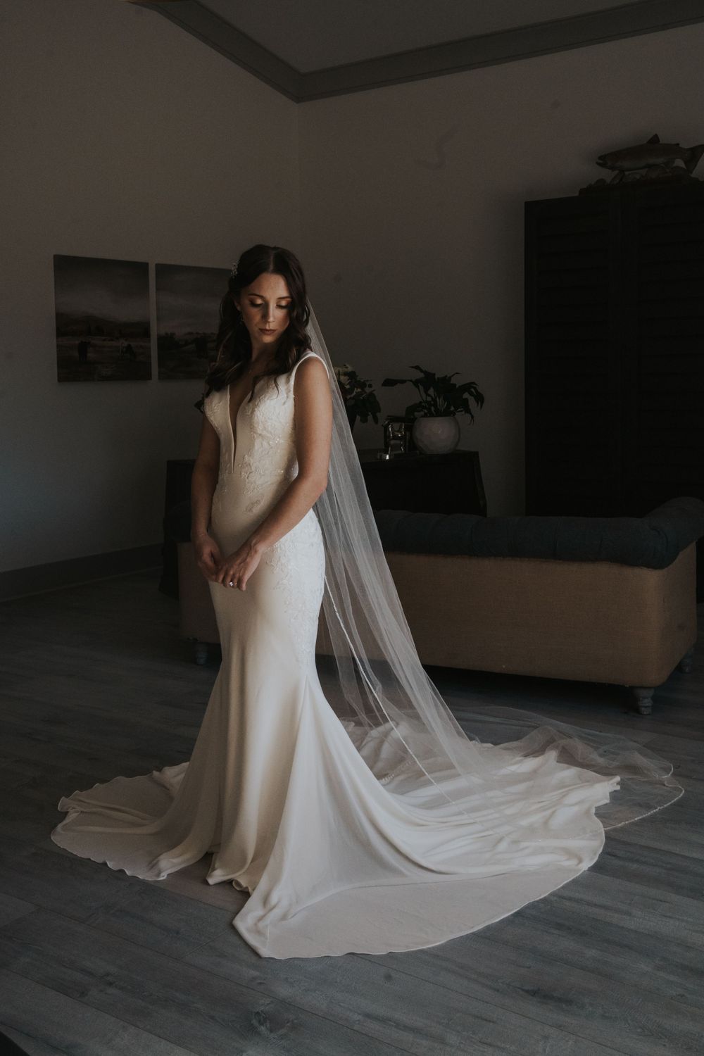 Bridal portraits in moody indoor lighting showing flowing train and veil details.