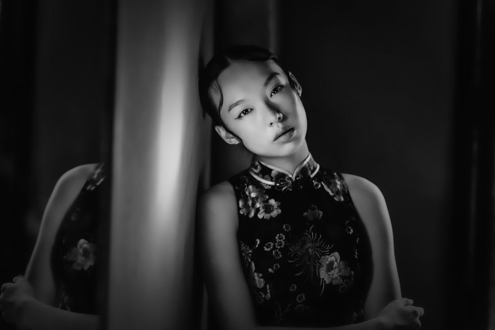 Artistic black and white portrait showing dramatic side lighting and elegant pose.