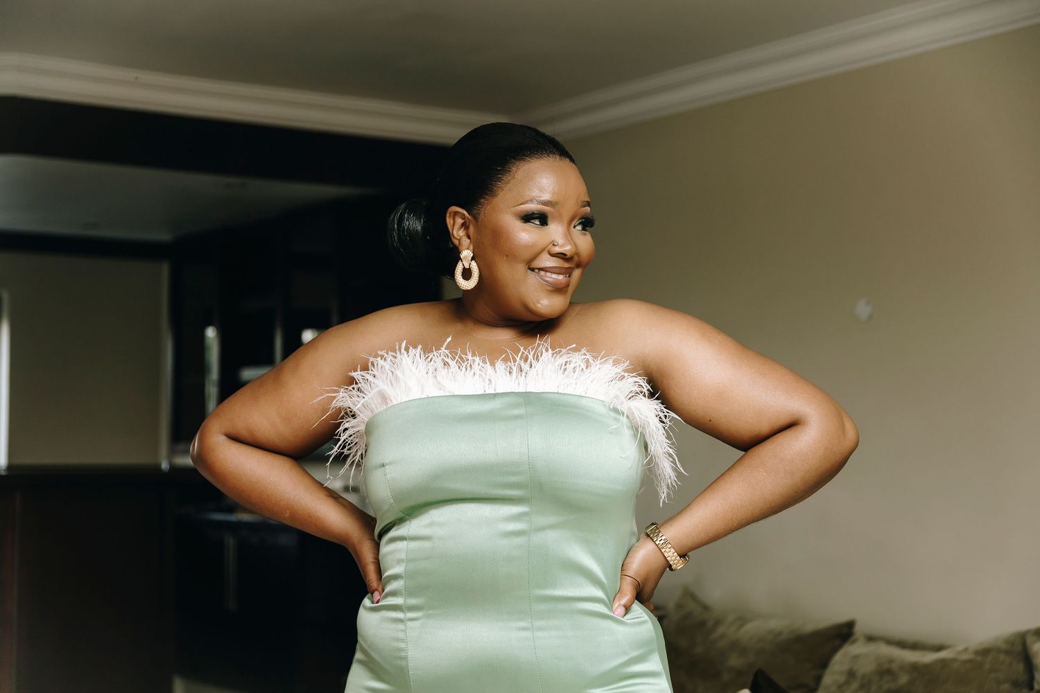 Woman in a mint green formal dress poses with hands on hips.