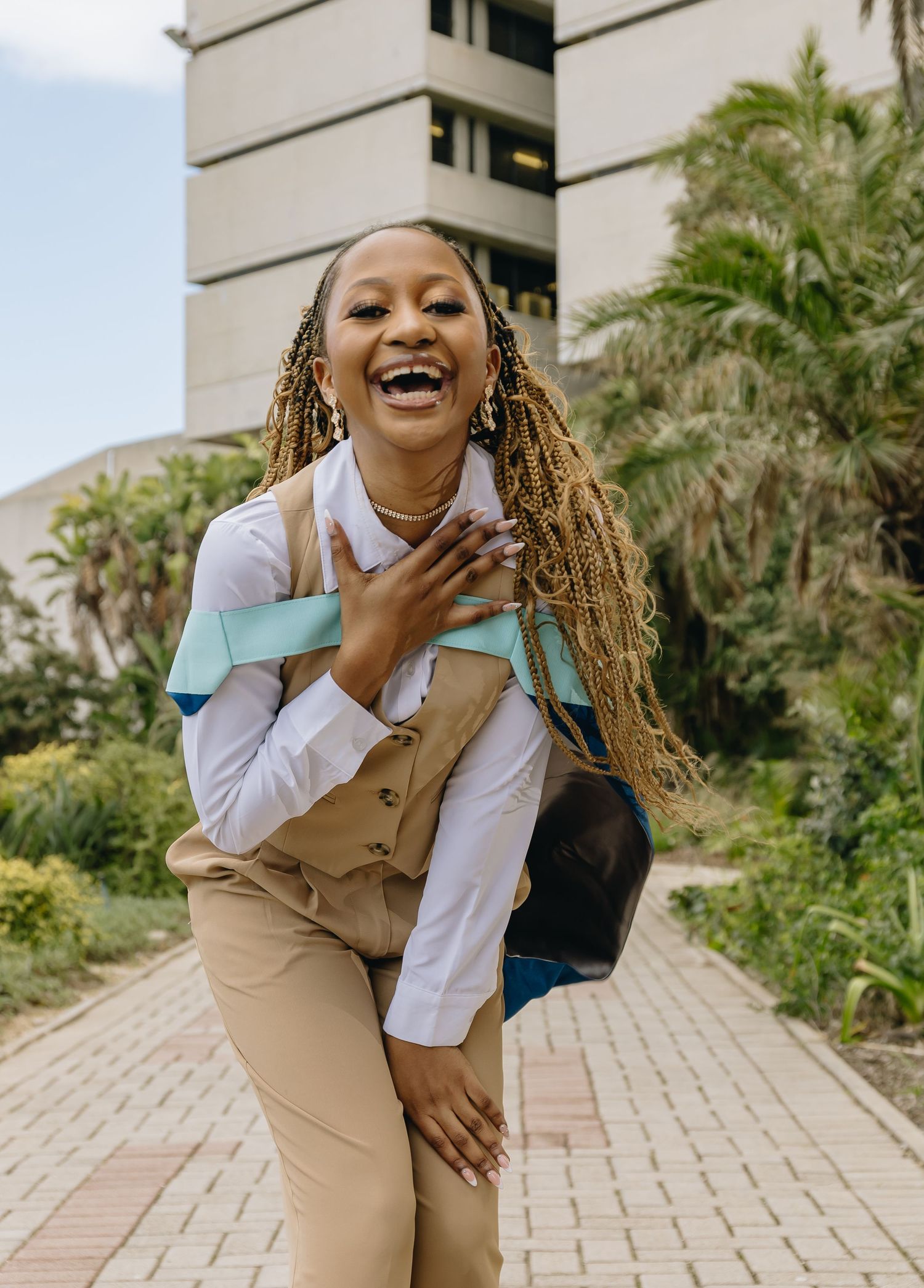 Energetic professional posing outdoors in business casual attire with long braids.