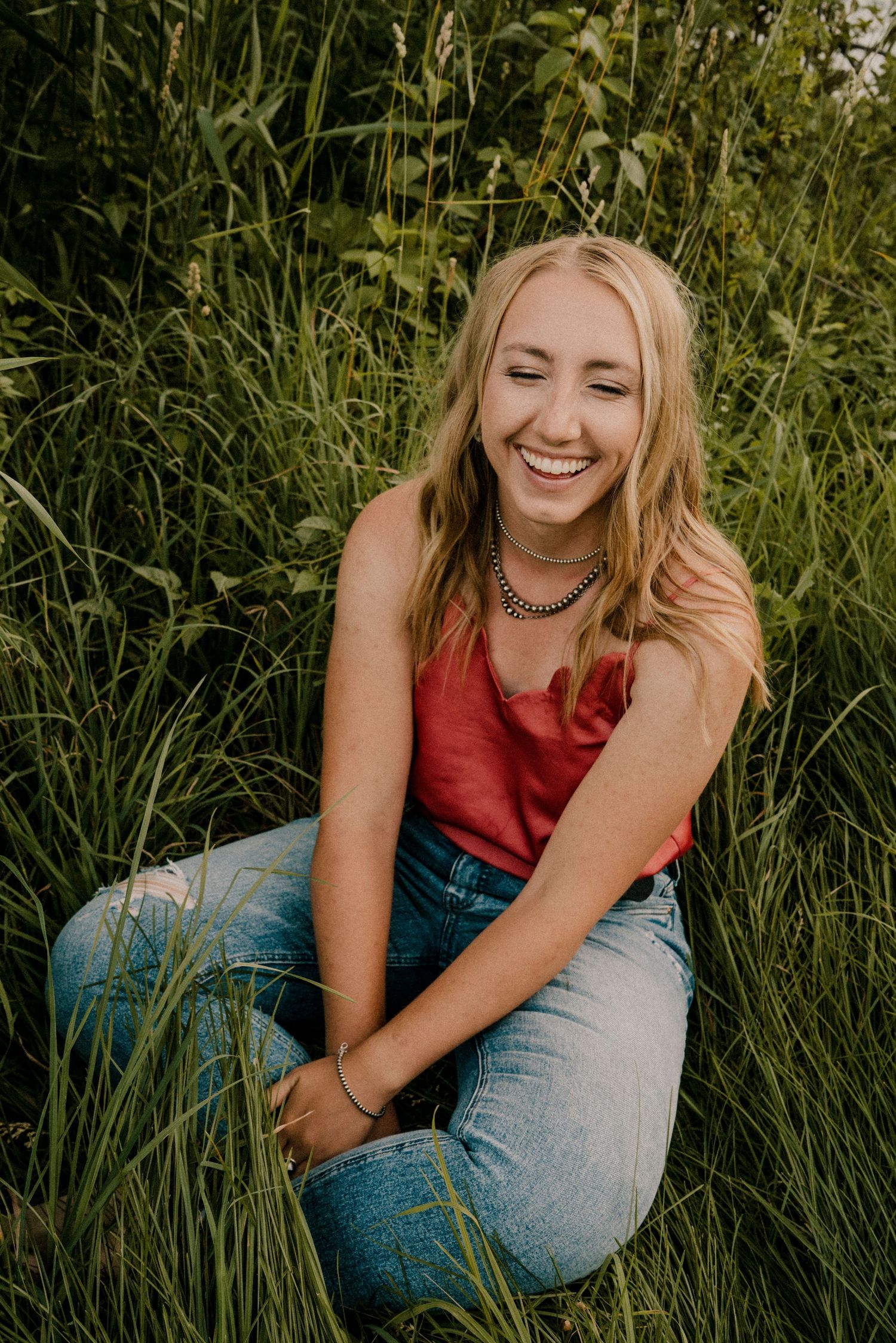 A young woman sitting in green grass laughing