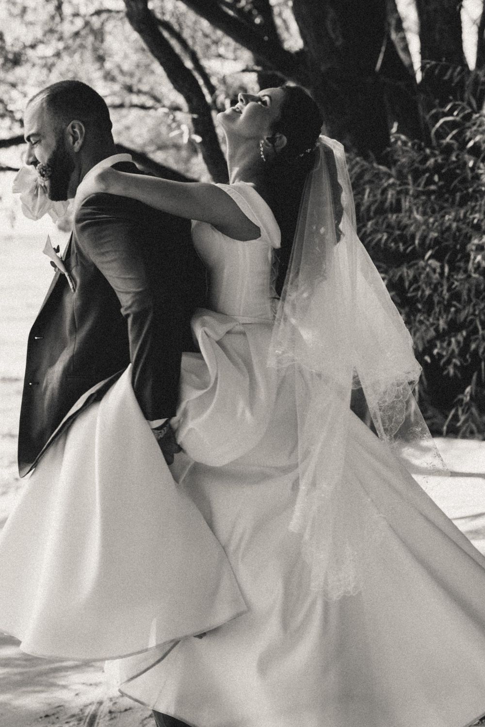 Black and white wedding photography showing romantic dance movements with flowing white dress.