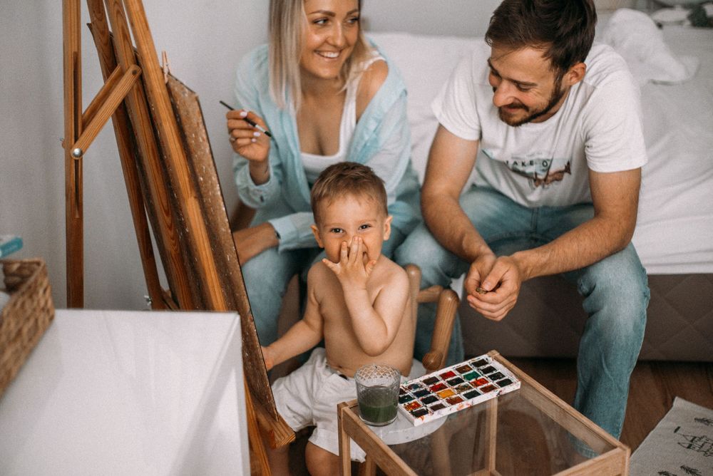 Family moment showing watercolor painting activity on wooden table.