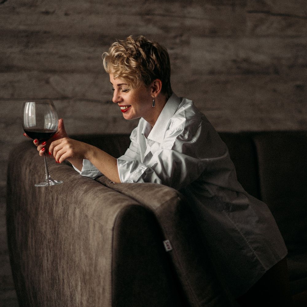 Moody sequence of someone resting against dark wooden surface with wine glass.