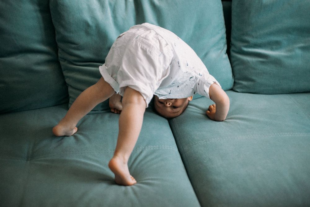 Close-up shots of small feet playing on a teal colored couch.