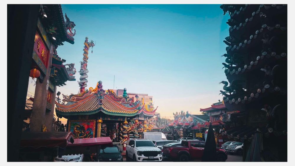 Vintage film photo of a busy street in Chinatown with traditional Asian architecture and parked cars at sunset.