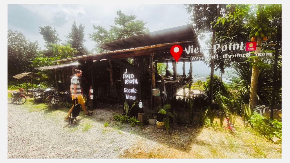 A rustic roadside cafe or store with a wooden structure and tropical plants in the surroundings.