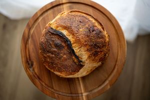Homemade crusty sourdough bread loaves cooling on wooden cutting boards in natural light.