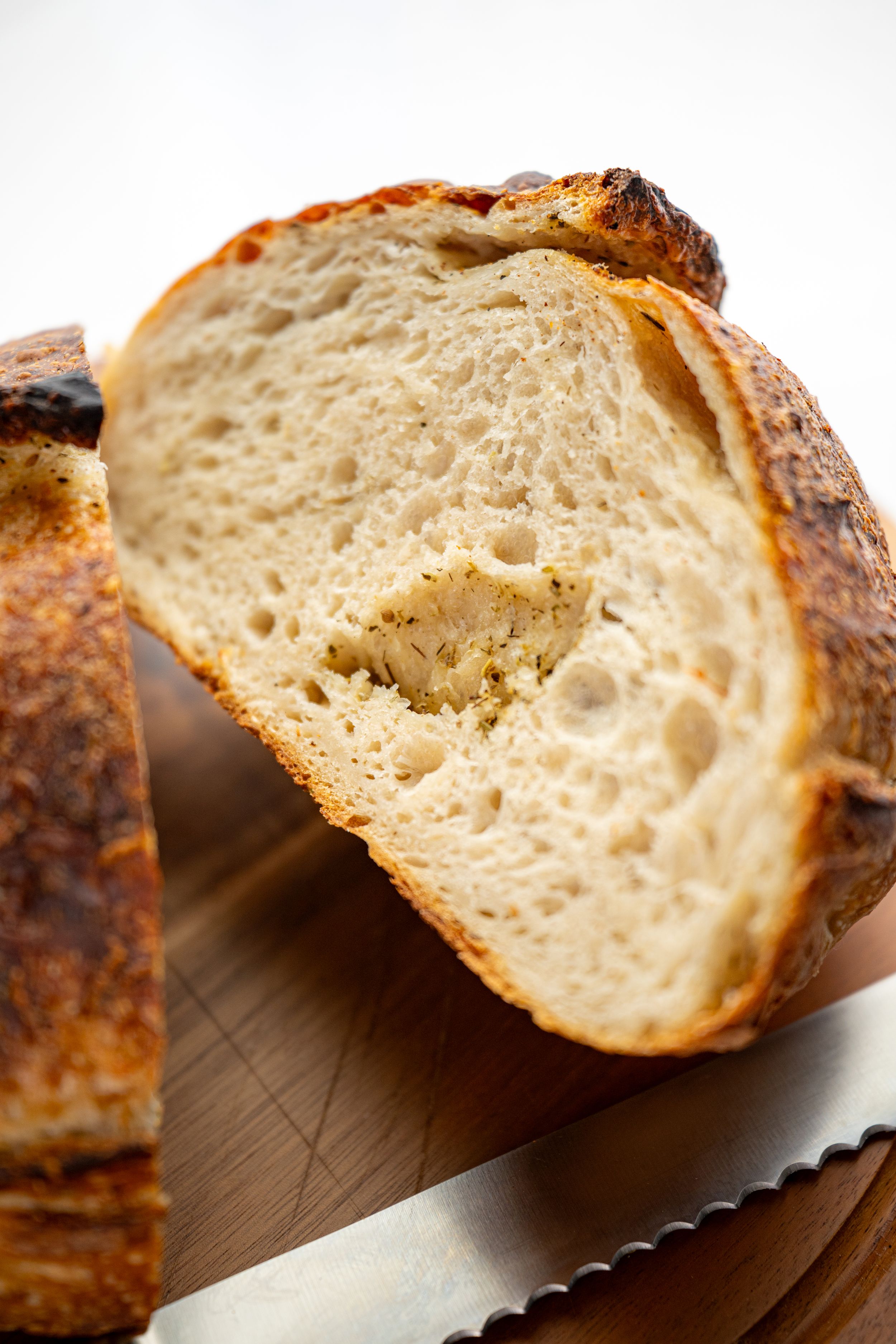 Close-up view of sliced artisanal sourdough bread showing its airy crumb structure and golden crust on a wooden surface.
