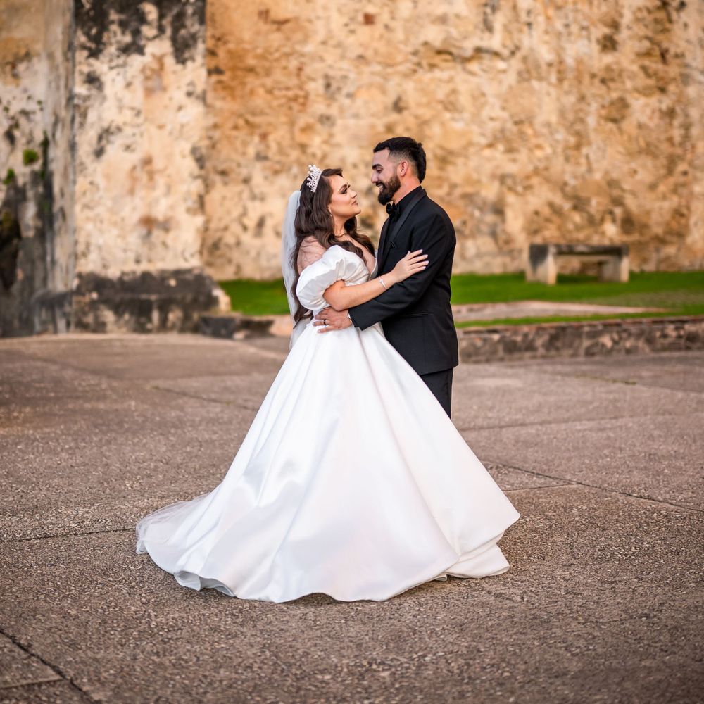 A romantic wedding dance pose in front of an old stone wall.
