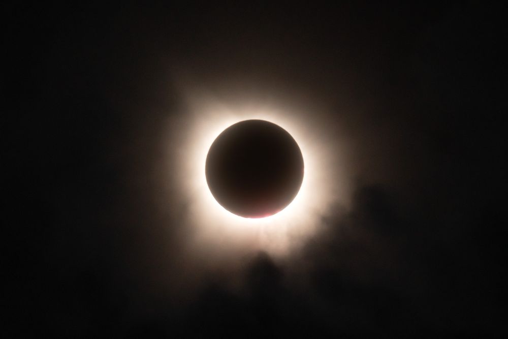 Solar eclipse with glowing corona ring surrounding the moon's silhouette in dark sky.