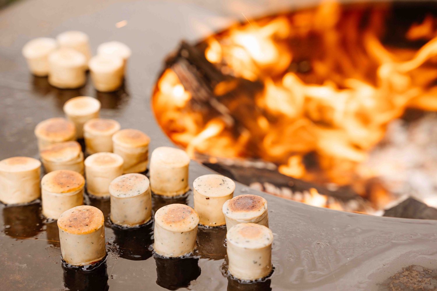 White appetizers arranged near flickering flames in atmospheric lighting.