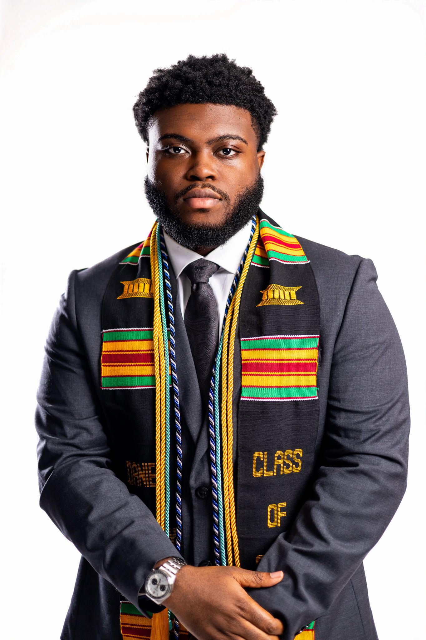 Graduate wearing grey suit and traditional African kente stole poses for professional graduation photos.