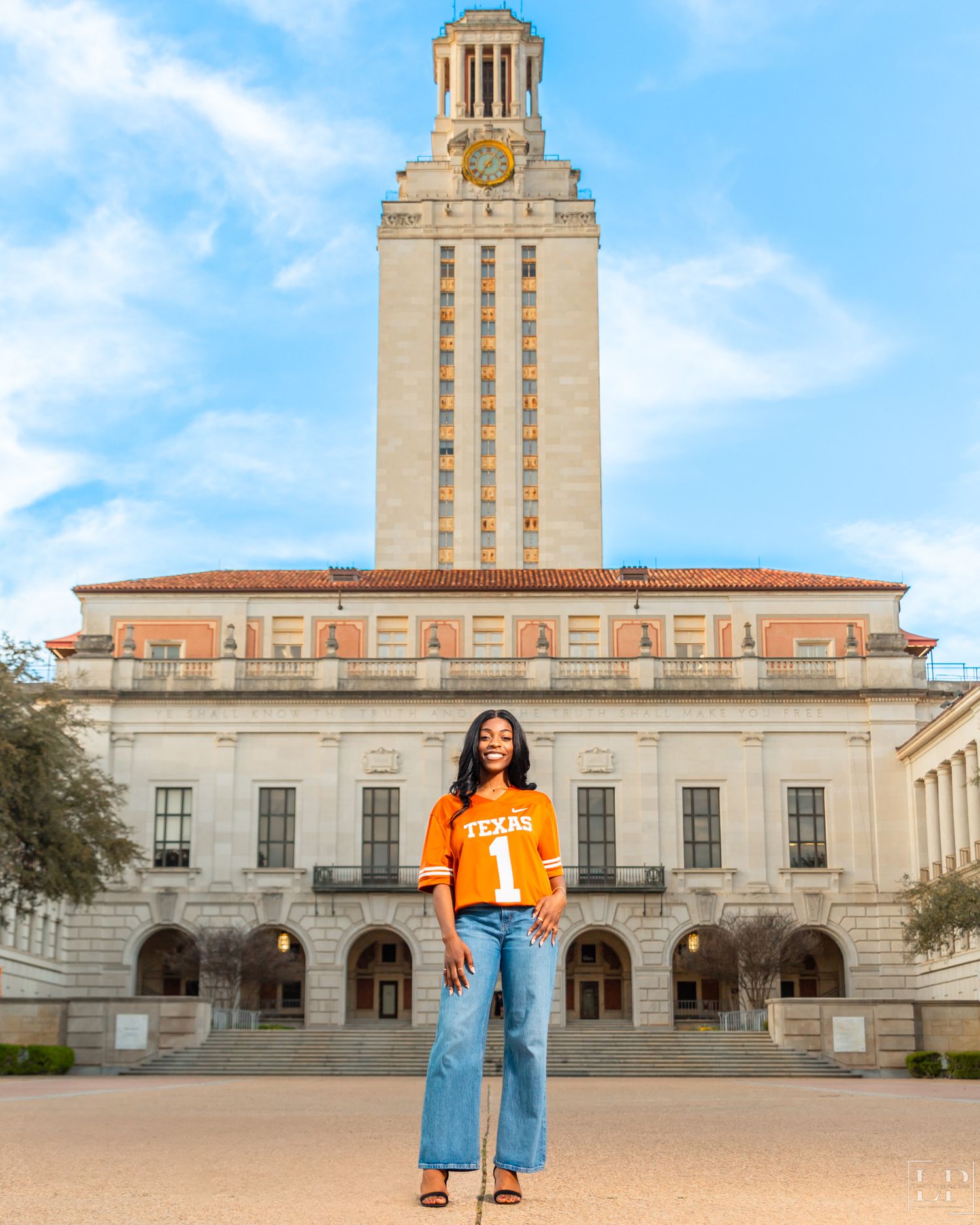The iconic University of Texas Tower and main building on a sunny day with blue skies.