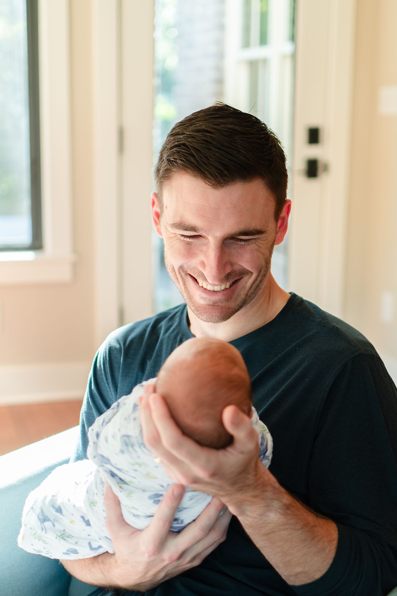 Dad holds swaddled baby during their in-home newborn photos.