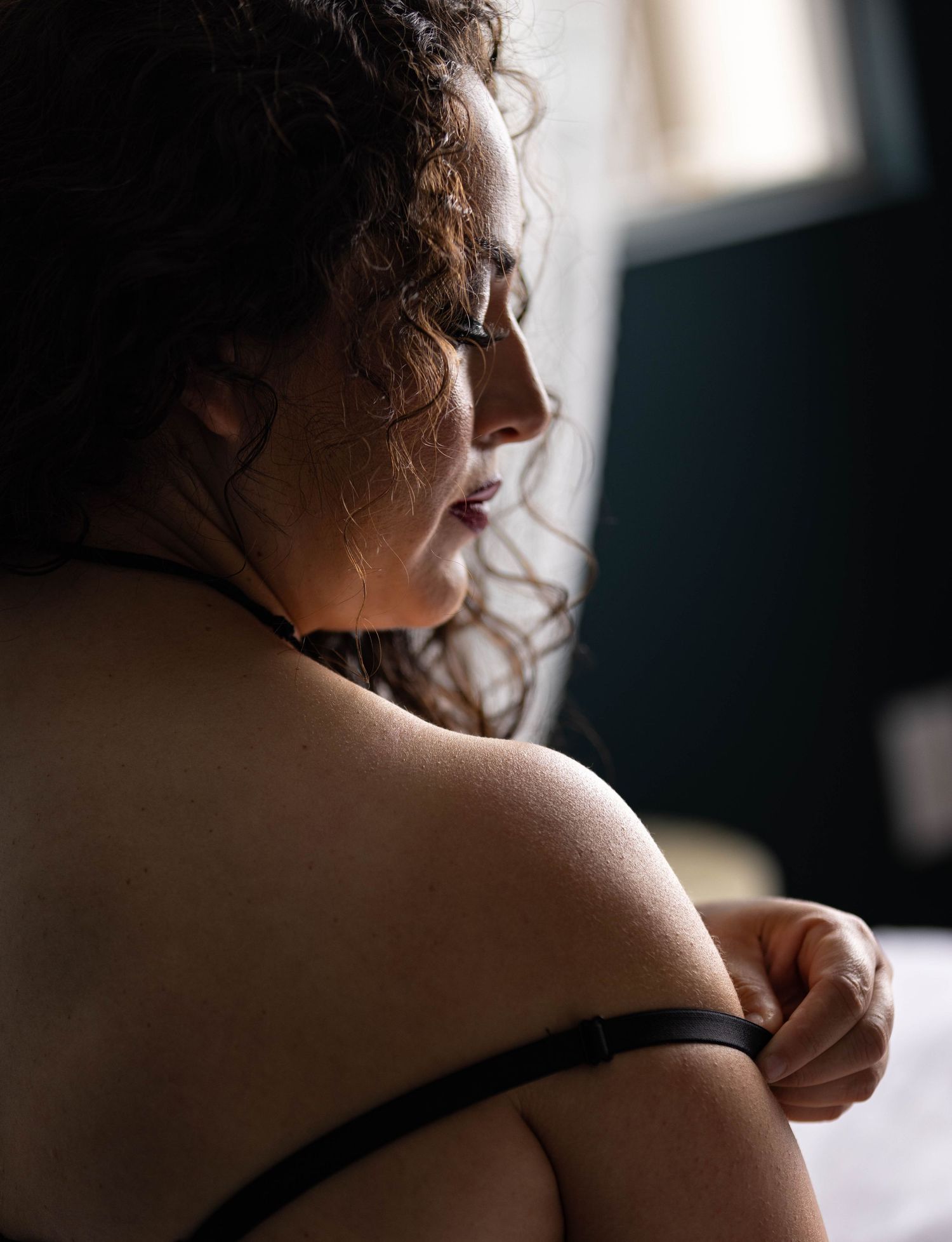 Los Angeles woman undressing during boudoir photo shoot.
