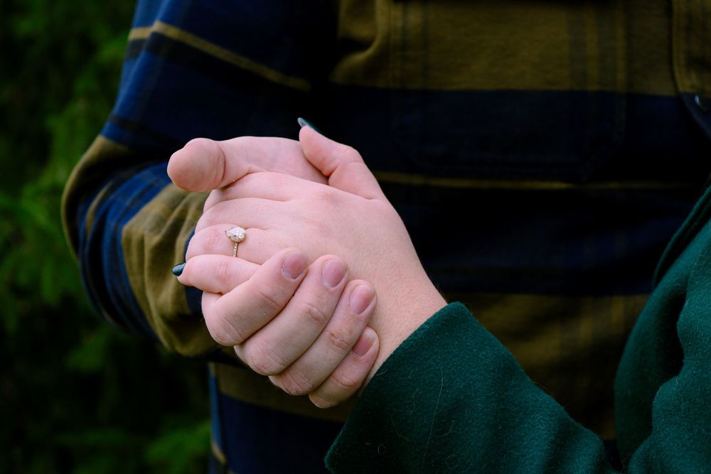 Close-up of two hands clasped together showing off an engagement ring.