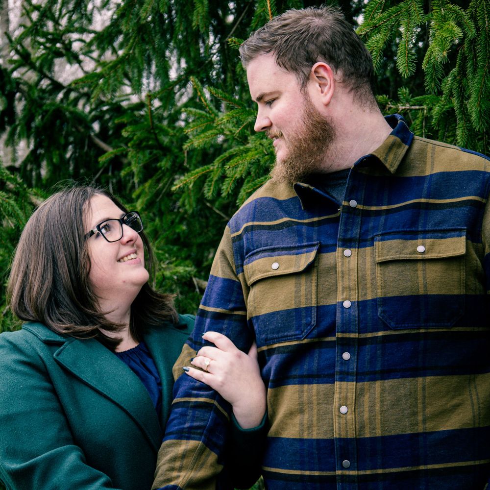 Couple sharing an intimate moment against evergreen trees.