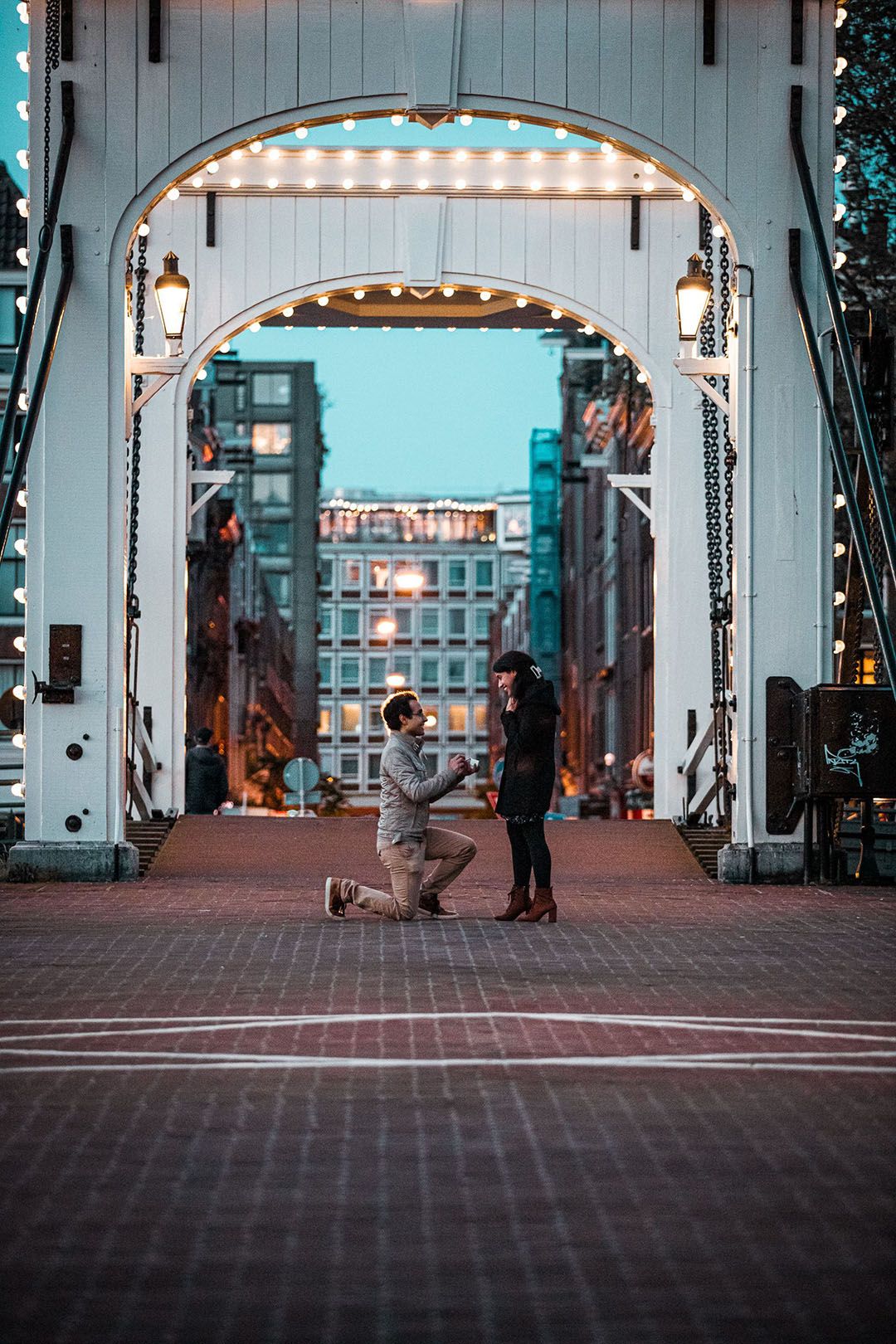 Man proposing marriage to woman at Magere Brug in Amsterdam